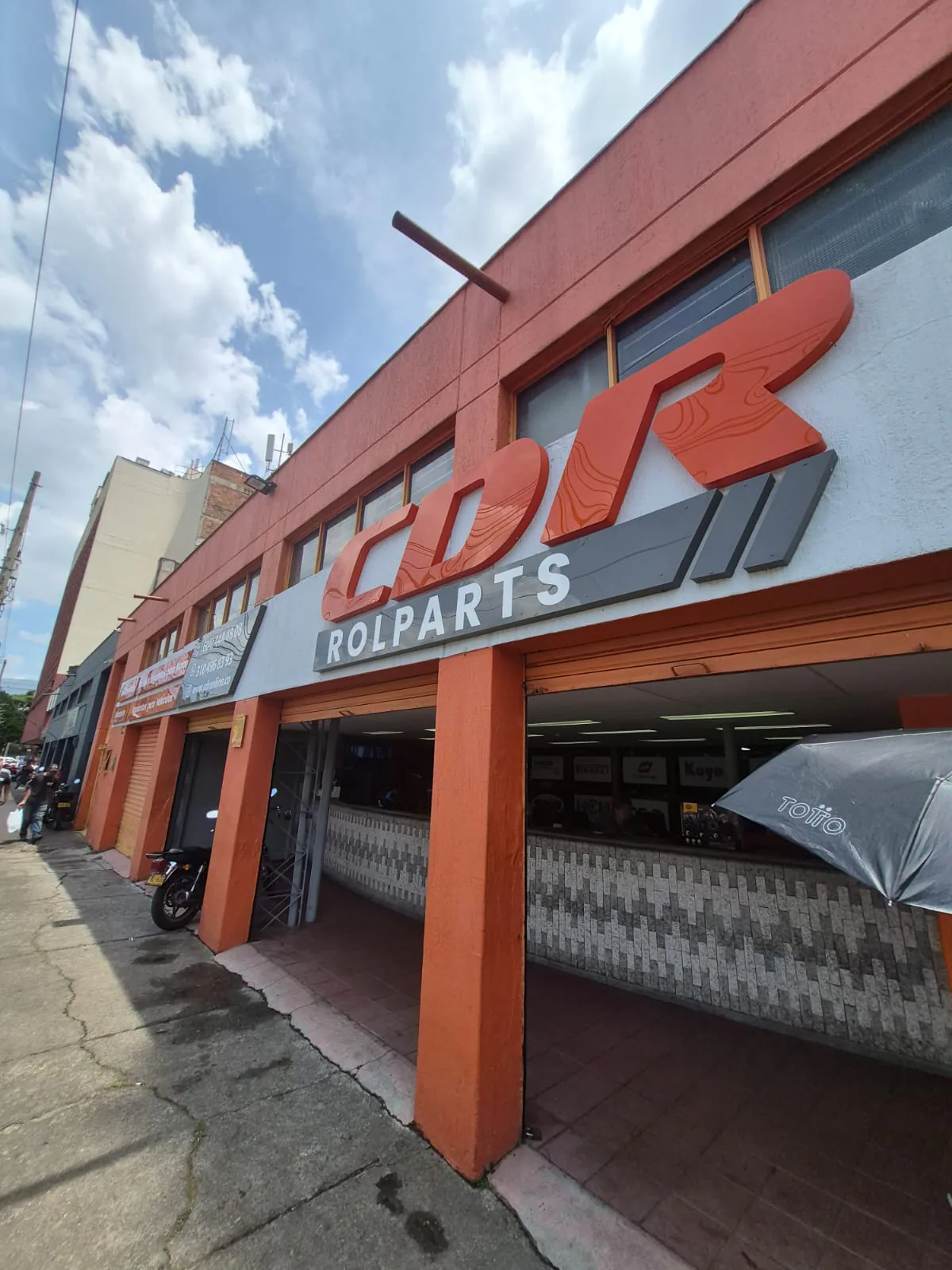 Aviso corpóreo CDR Rolparts sobre fachada naranja